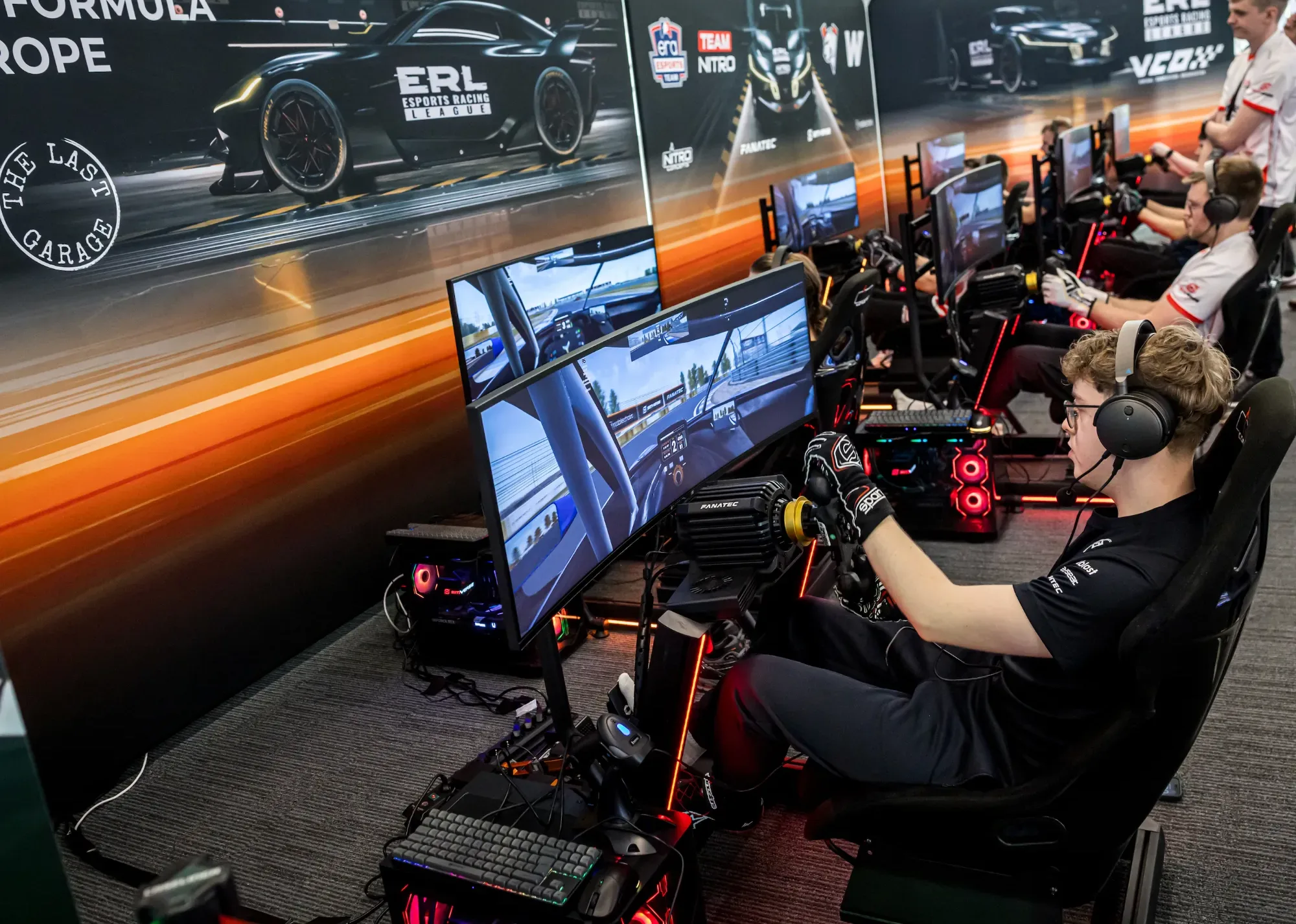 ERL teams racing side by side in a row of sim rigs in front of the Esports Racing League wall