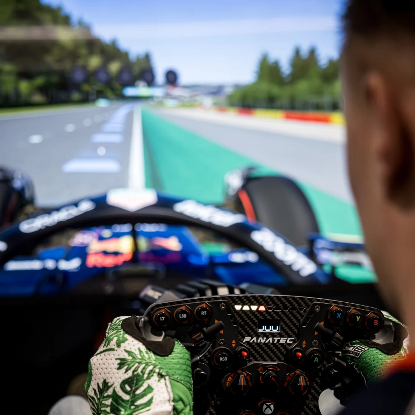 A sim racer behind a Fanatec wheel, an F1 cockpit filling the screen ahead