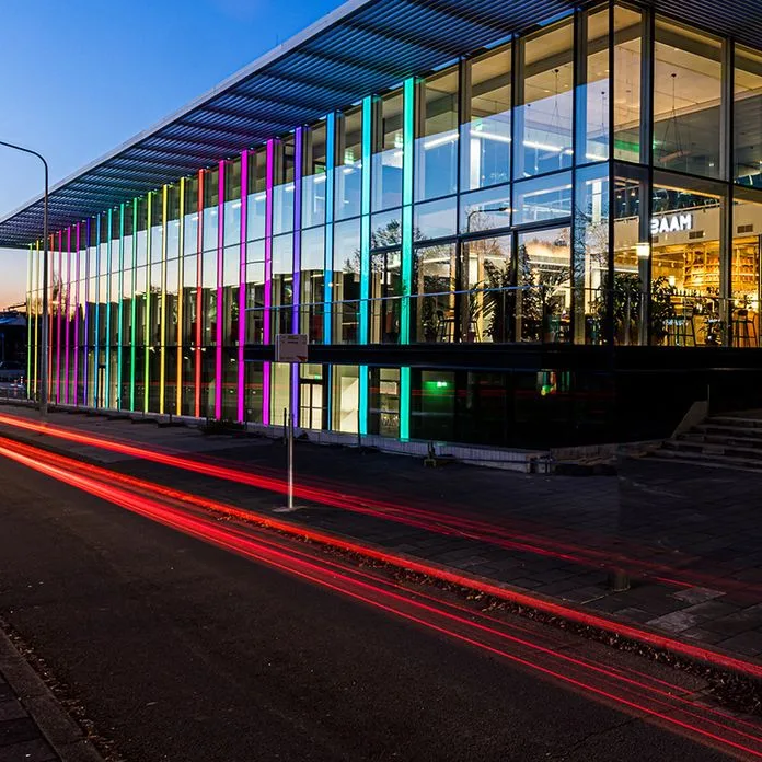 MECC Maastricht at dusk, its glass facade lit in colour